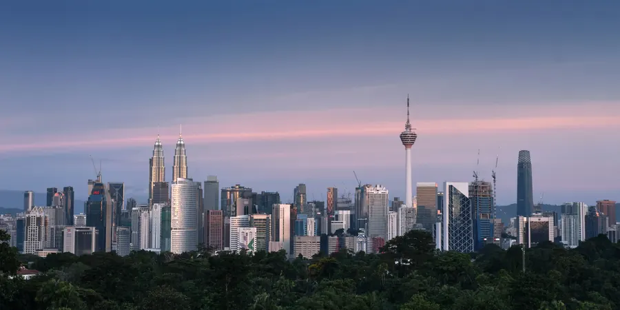 Latar langit Kuala Lumpur waktu senja, dilihat dari balik pepohonan